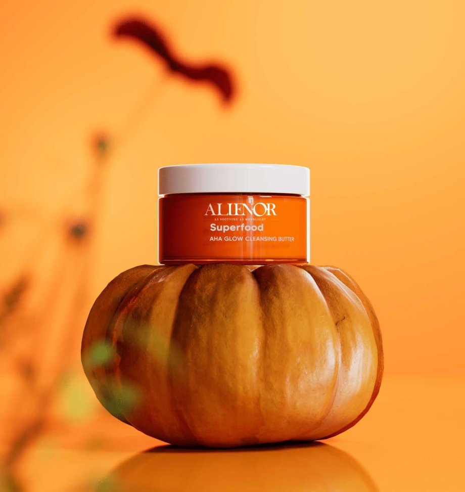 Alienor Superfood AHA Glow Cleansing Butter product photography with vibrant orange packaging on a pumpkin